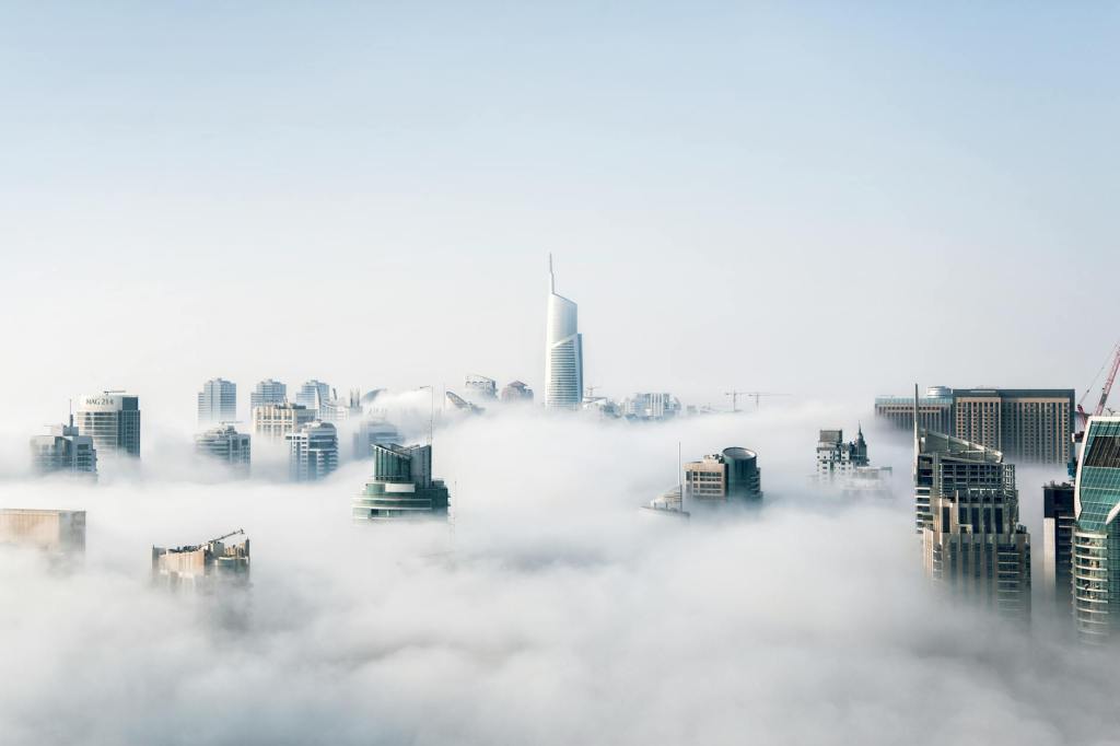 A view of a city skyline partially enveloped in fog, showcasing tall buildings reaching above the clouds.